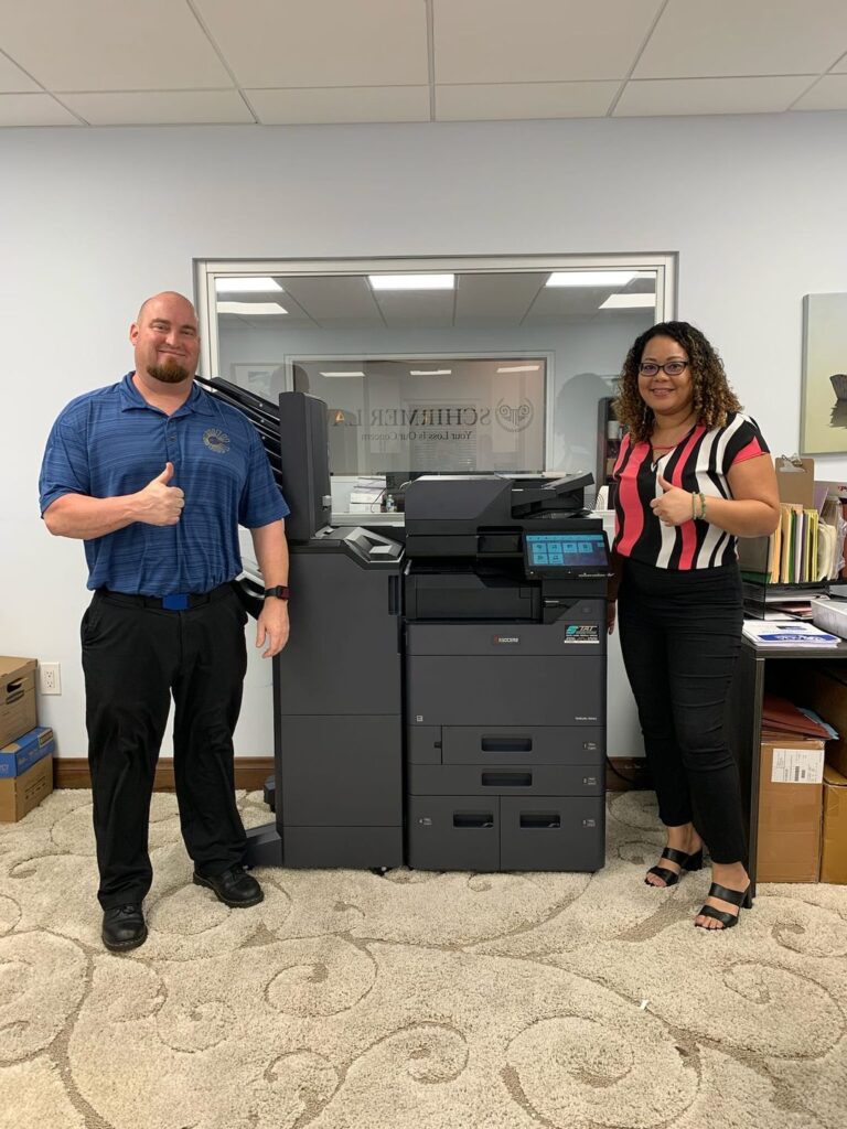 Two clients pictured with a new copy machine for their office in South Florida